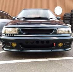 the front end of a black car parked in a parking lot