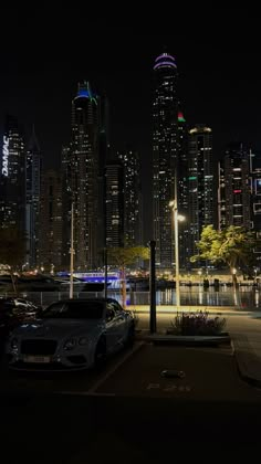 the city skyline is lit up at night, with cars parked on the side of the street