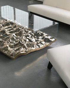 a glass coffee table with an abstract design on it's top and bottom, in front of a white couch