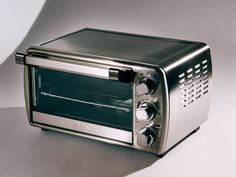 a toaster oven sitting on top of a white table next to a silver wall