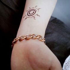 a woman's arm with a tattoo on it and a chain around the wrist