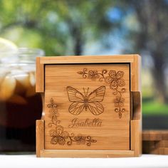 a wooden box with a butterfly on it and some drinks in the backround