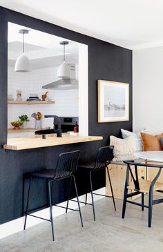 a living room filled with furniture next to a dining table and two chairs near a kitchen counter