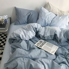 an unmade bed with blue sheets and checkered flooring next to a nightstand