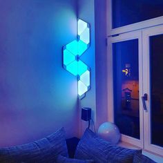 a living room filled with furniture and a blue light on the wall next to a window