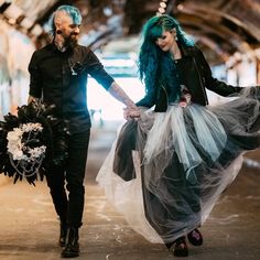 a man and woman holding hands while walking through a tunnel with flowers in their hair