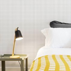 a bed with a yellow and white bedspread next to a lamp on a table