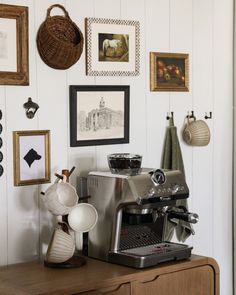 a coffee maker sitting on top of a wooden table next to pictures and other items