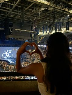 a woman making a heart shape with her hands at a sporting event in an arena