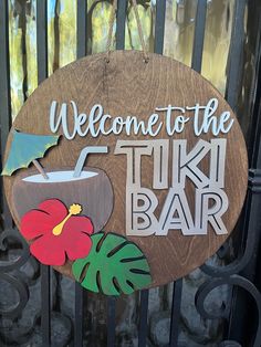 a wooden sign that says welcome to the tiki bar with a flower on it