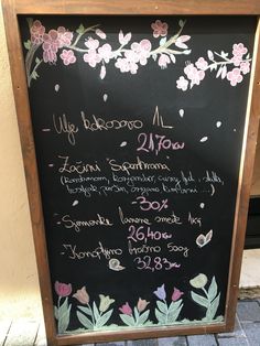 a chalkboard sign with writing on it and flowers painted on the side of it