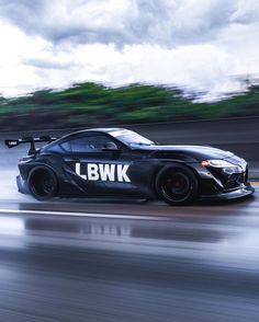 a black sports car driving down a wet road