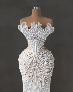 the back of a white wedding dress on a mannequin headdress in front of a black background