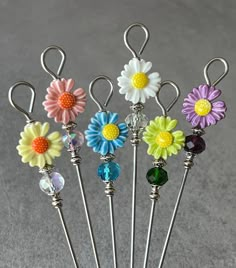 six different colored flowers are sitting in a holder on a gray surface with silver wire