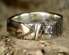 a silver ring sitting on top of a piece of wood with a diamond in it