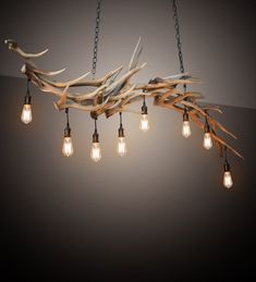 a chandelier made out of branches and light bulbs hanging from it's sides