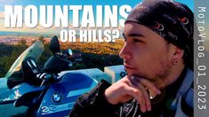 a man sitting on top of a motorcycle in front of a blue sky with the words mountains or hills?