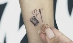 a person is holding a penny with a tattoo on their arm that says i love you