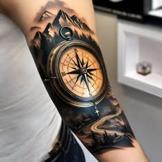 a man's arm with a compass tattoo on it and mountains in the background