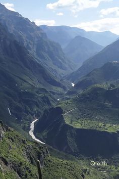 a valley with mountains in the background and a river running through it that is surrounded by greenery