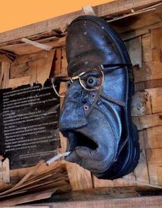 an old blue leather shoe with glasses on it's head and mouth is shown in front of a wooden wall