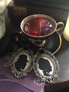 a cup of tea and two coasters with silhouettes on them sitting on a table