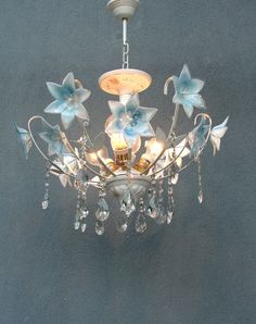 a chandelier with blue flowers hanging from it's center point and crystal drops on the bottom