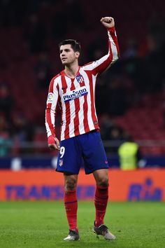 a soccer player holding his fist up in the air while standing on top of a field