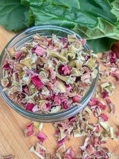 a glass bowl filled with pink and yellow flowers on top of a wooden cutting board