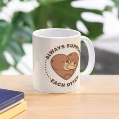 a coffee mug that says, always support each other with a bear hugging it's face