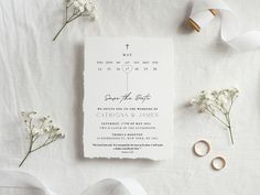 the wedding stationery is laid out with flowers and rings