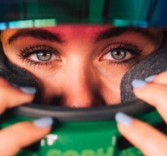 a close up of a person wearing a helmet and holding a coffee cup in front of their face