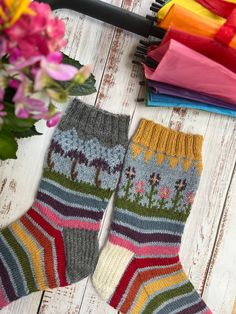 two knitted socks sitting on top of a wooden floor next to flowers and umbrellas