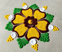 a yellow and brown flower with green leaves on the floor next to some white balls