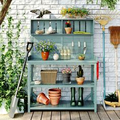 an outdoor garden with potted plants and gardening tools on shelves next to a brick wall