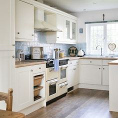 a kitchen with white cabinets and wooden floors