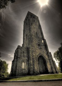 the sun shines brightly on an old stone building with grass and trees around it