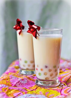 two glasses filled with liquid sitting on top of a colorful table cloth covered tablecloth