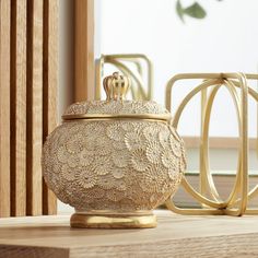 a gold vase sitting on top of a wooden table next to other items and decor