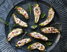 several stuffed peppers on a plate with herbs