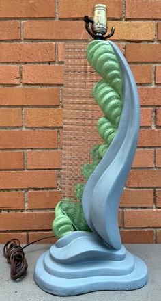 a blue and green lamp sitting on top of a table next to a brick wall