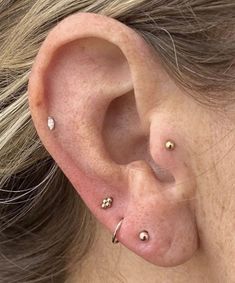 a close up of a person's ear with three piercings