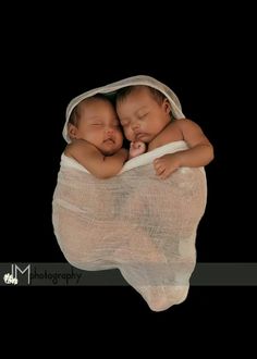 two baby babies are sleeping in a white cloth wrapped around each other on a black background