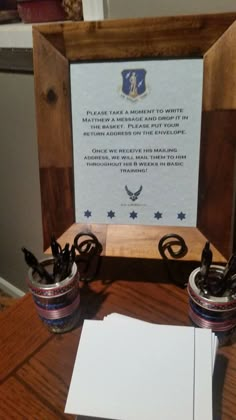 two small vases sitting on top of a wooden table next to a framed sign