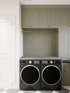 a washer and dryer are in the middle of a laundry room with cabinets