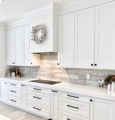 a kitchen with white cabinets and a wreath on the wall