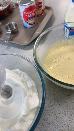 two bowls filled with whipped cream on top of a counter next to an electric mixer