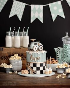 a birthday cake with cars on it sitting in front of other desserts and snacks