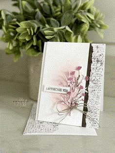 a close up of a card on a table near a potted plant with flowers