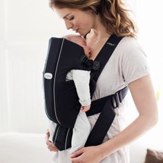 a woman holding a baby in a black and white sling